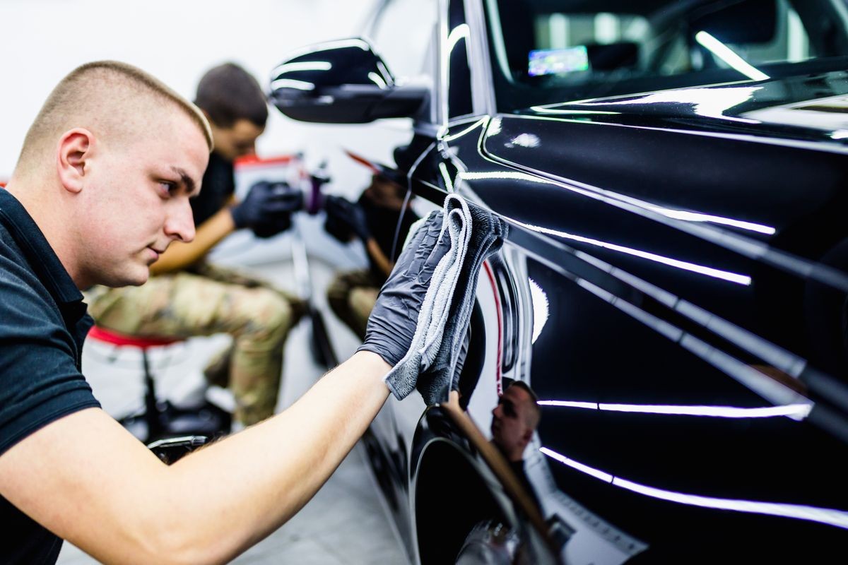 A man cleaning car with cloth, car detailing (or valeting) concept. Selective focus.